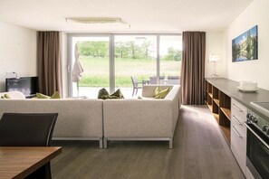 A modern room with a sofa, a dining table, a TV, and a kitchen area. - Apartment in Radstadt with swimming pool (Radstadt)
