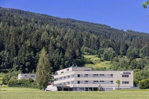 A multi-story building with a flat roof, surrounded by a forested hillside. - Apartment in Radstadt with swimming pool (Radstadt)