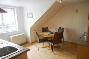 A dining area with a round table, chairs, and a clock on the wall. - Holiday apartment Brigitte DG (Flörsbachtal)