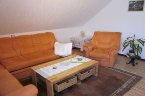 A cozy living room with a sofa, armchair, and a coffee table. - Holiday apartment Brigitte DG (Flörsbachtal)