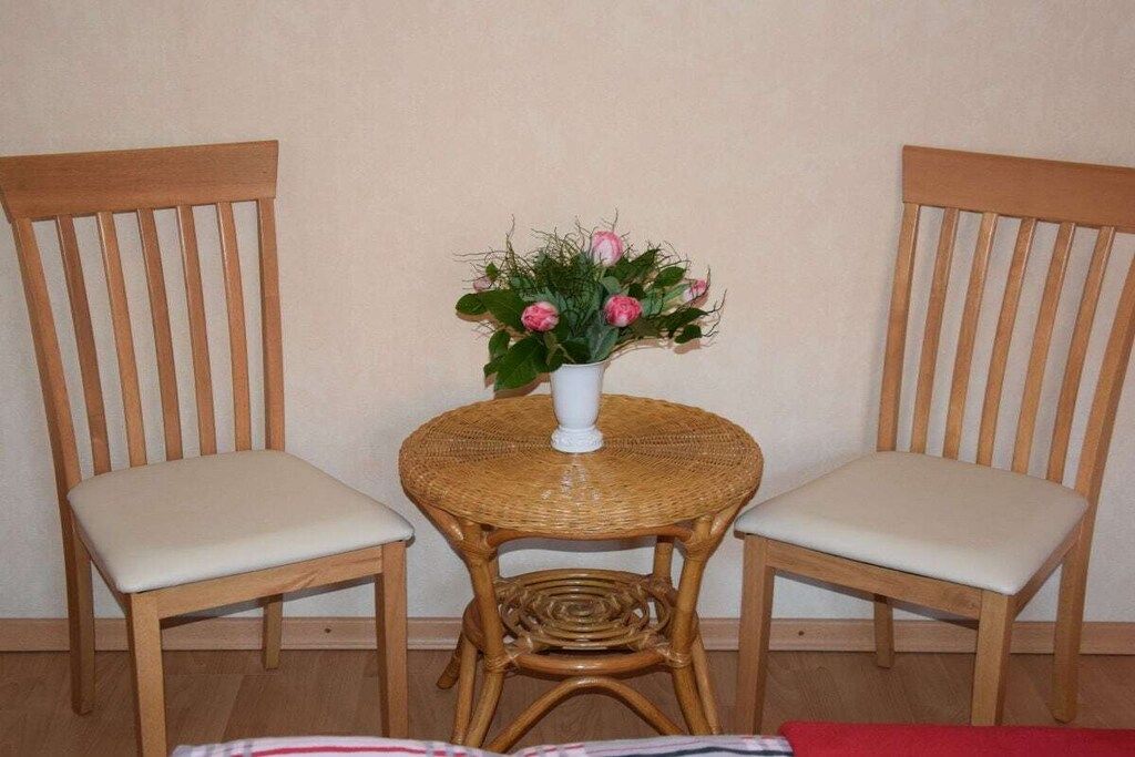 Two wooden chairs with cushioned seats and a small round table with a woven top.