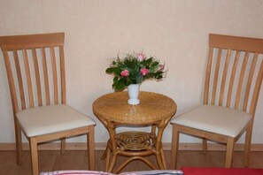 Two wooden chairs with cushioned seats and a small round table with a woven top. - Langeoog im Haus - North Sea Islands (Dornum)