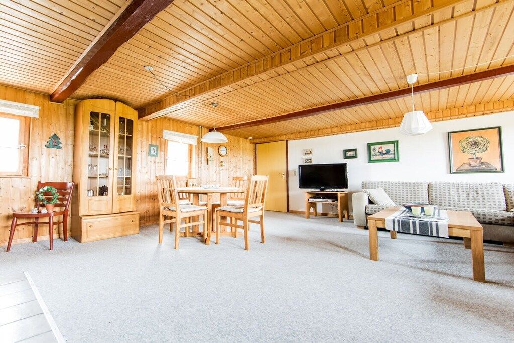 Een houten interieur met een eethoek, een bank en een televisie.
