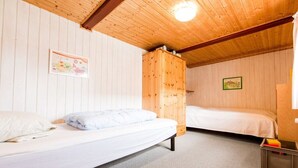 A room with two beds, wooden walls, and a ceiling light. - Nydamsgaard "hus mælkebøtte" (Faaborg \/ Bojden)