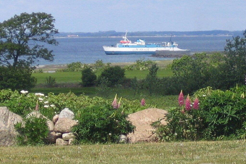 A boat on a body of water with a grassy area and rocks in the foreground.