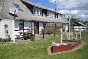 A traditional building with a sloped roof, a wooden bench, and a picnic table. - Nydamsgaard "hus mælkebøtte" (Faaborg \/ Bojden)