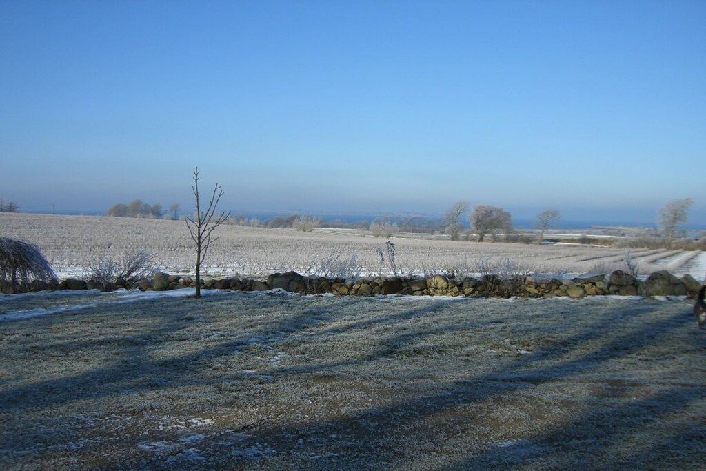 Een landelijk landschap met een stenen muur, een heldere lucht en een verre horizon.