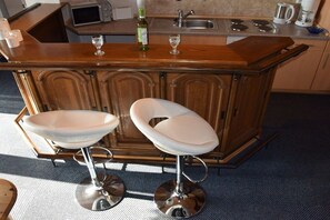 A kitchen with a wooden bar and two white bar stools. - Baltrum in the North Sea Islands House (Dornum)