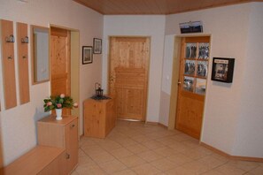 A hallway with wooden doors, a small cabinet with a vase, and a tiled floor. - Baltrum in the North Sea Islands House (Dornum)