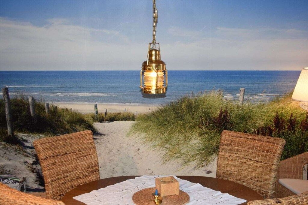 A beachside dining area with wicker furniture, a hanging lantern, and a view of the ocean.