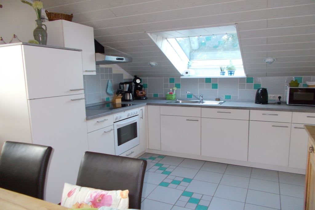 A compact kitchen with white cabinets, a built-in oven, a microwave, and a skylight above the sink.