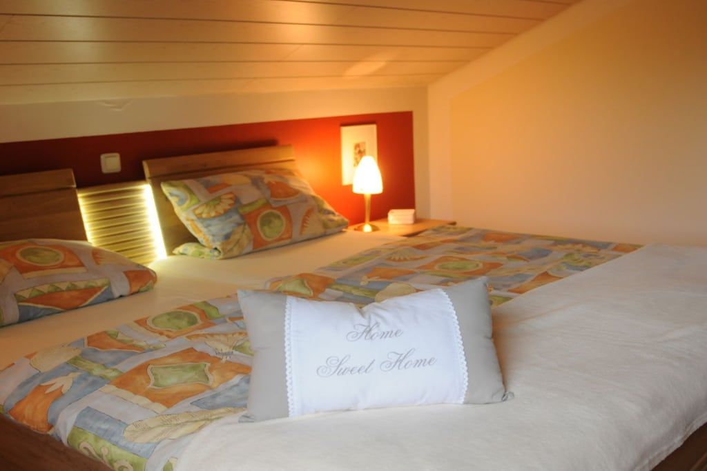 A bedroom with a bed, pillows, a bedside lamp, and a headboard.