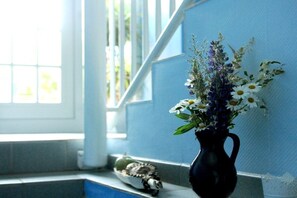 Eine Vase mit Blumen auf einem Fensterbrett, ein kleines Dekorationsstück und ein Fenster mit Blick.