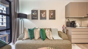 Una sala de estar moderna con sofá, cojines, una lámpara de pie y tres cuadros enmarcados en la pared.