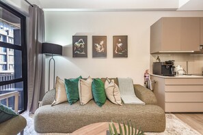 Un soggiorno moderno con un divano, cuscini, una lampada da terra e tre opere d'arte incorniciate al muro.