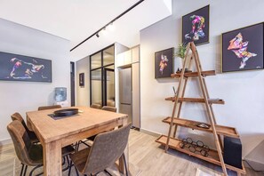 Ein moderner Büroraum mit einem Holztisch für Besprechungen, Stühlen, einem Himmelsregal und abstrakter Kunst an den Wänden.