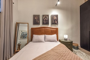 Una camera da letto con un letto grande, un comodino con una lampada e tre quadri appesi al muro.