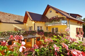 A two-story building with a balcony, surrounded by flowering plants. - Holiday apartment with 1 bedroom (Vogtsburg-Oberbergen)
