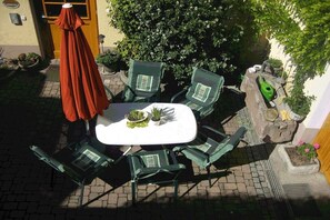 An outdoor patio with a table and chairs, surrounded by potted plants and a small rock feature. - Holiday apartment with 1 bedroom (Vogtsburg-Oberbergen)