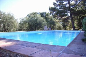 Ein rechteckiger Swimmingpool mit glasklar blauem Wasser, umgeben von einer Steinbordwand.