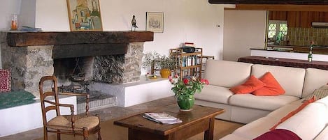 Una sala de estar con chimenea, un sofá, una mesa de centro de madera y una silla.