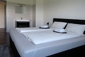 A modern hotel room with a large bed, a bedside table, a mirror, and a bathroom with a sink. - City view Winterberg (Winterberg)
