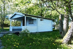 A small white cabin with a porch, surrounded by trees and grass. - City view Winterberg (Winterberg)