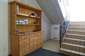 A wooden bookcase with multiple shelves and drawers, a staircase with a metal railing, and a door in the background. - City view Winterberg (Winterberg)