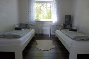 Ein Zimmer mit zwei Betten, einem Heizkörper, einem Fenster mit Vorhängen und einer sternförmigen Dekoration an der Wand.