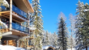 Um edifício com várias andares e varandas, rodeado por árvores cobertas de neve.