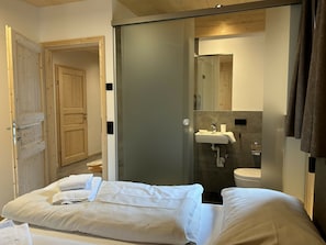 A hotel room with a bed, a bathroom with a sink and toilet, and a wooden door. - Superior Chalet # 8 With Sauna & Hot Tub (Stadl-Predlitz)