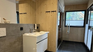 Casa de banho moderna com lavatório branco, espelho e sanita.
