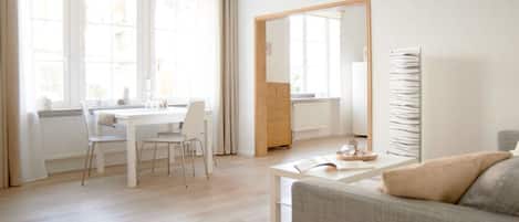 Una sala de estar luminosa y moderna con comedor, sofá y mesa de centro.