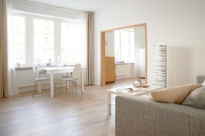 Una sala de estar luminosa y moderna con comedor, sofá y mesa de centro.