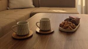 Un espacio de sala acogedor con un sofá, dos tazas en posavasos y una bandeja de galletas.