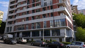 Un immeuble résidentiel à plusieurs étages, doté de balcons, de grandes fenêtres et d’un espace de stationnement à l’avant.