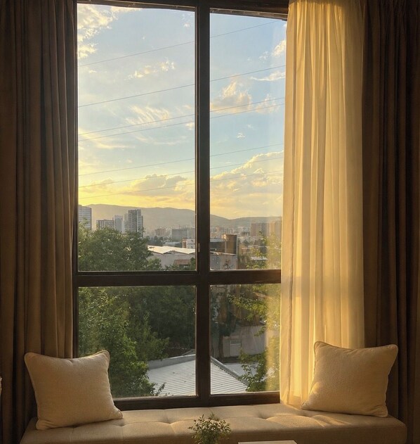 Una habitación con un ventanal grande, un banco acolchado y cortinas.