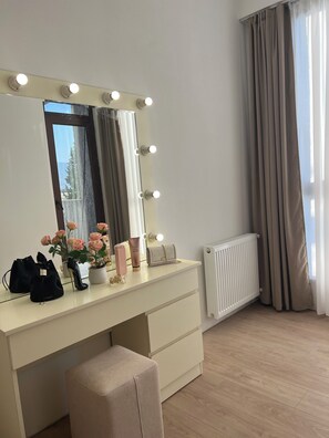 A room with a vanity, a mirror with lights, a radiator, and a window with curtains. - Bright & Cozy 2-Bedroom Apartment in Tbilisi, Just a 5-Minute Walk from the Metro (T'bilisi)