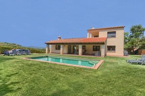 Une maison à deux étages avec une piscine, un patio couvert et une pelouse.