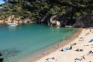 A beach with clear turquoise water, a boat, and people sunbathing. - Villa Helma in Begur (Begur)