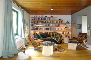 Un salon chaleureux avec une cheminée, une bibliothèque et un coin salon confortable.