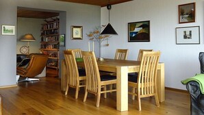 A dining area with a wooden table and chairs, a bookshelf, and a lamp. - Henriette's holiday home (Bad Harzburg)