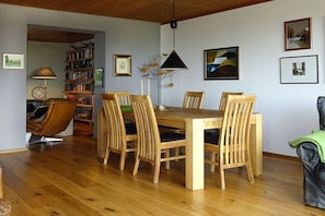 Ein Essbereich mit Holztisch und -stühlen, einem Bücherregal und einer Lampe.