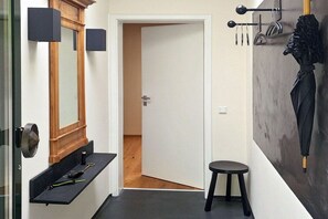 A hallway with a mirror, a coat rack, a stool, and a door leading to another room. - Henriette's holiday home (Bad Harzburg)