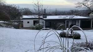 A modern house with a flat roof, a garage, and a snow-covered landscape. - Henriette's holiday home (Bad Harzburg)
