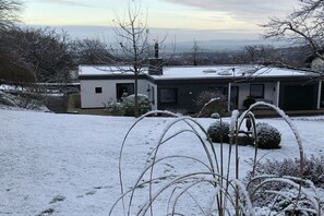 Ein modernes Haus mit flachem Dach, einer Garage und verschneiter Landschaft.