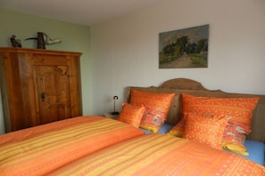 Ein Schlafzimmer mit einem Bett, einem Holzschrank und einem Gemälde an der Wand.