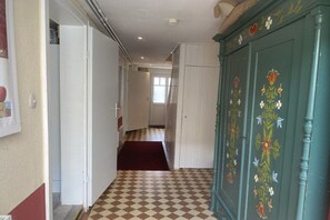 A hallway with a checkered floor, a red carpet, and a green cabinet with floral designs. - Holiday home with 2 bedrooms (Bodenwerder)
