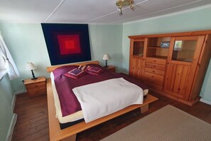 A bedroom with a bed, wooden wardrobe, two bedside tables, and a red accent wall. - Holiday home with 2 bedrooms (Bodenwerder)
