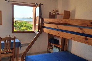 A room with a bunk bed, a desk, and a window overlooking greenery and a body of water. - Holiday home in Gruissan with swimming pool (Gruissan)